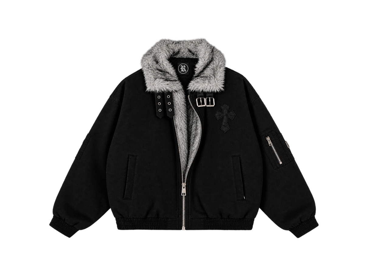 A black bomber jacket with a gray faux-fur collar, featuring a front zipper, silver-tone hardware, a cross patch on the chest, and a zippered sleeve pocket, shown against a plain white background.